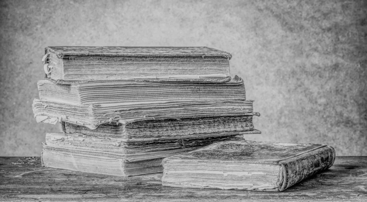 Ein Stapel Bücher von Oberer Block auf einem Holztisch in Schwarz und Weiß.