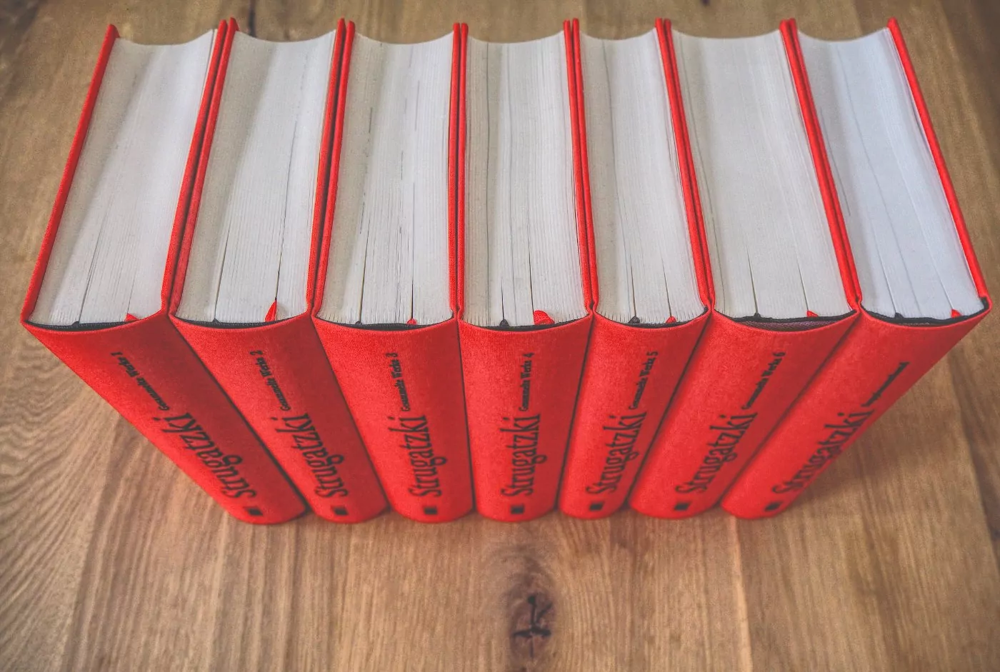 Ein Stapel roter Bücher auf einem Holztisch.