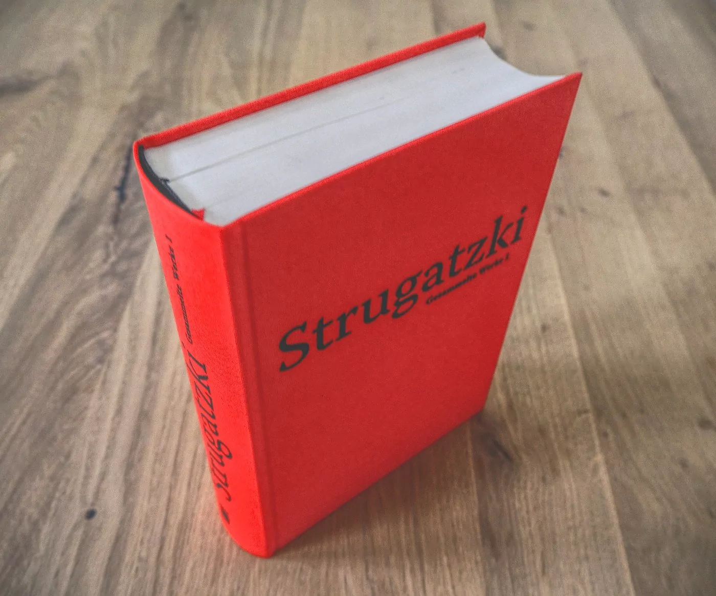 Ein rotes Buch mit schwarzem Einband auf einem Holztisch.