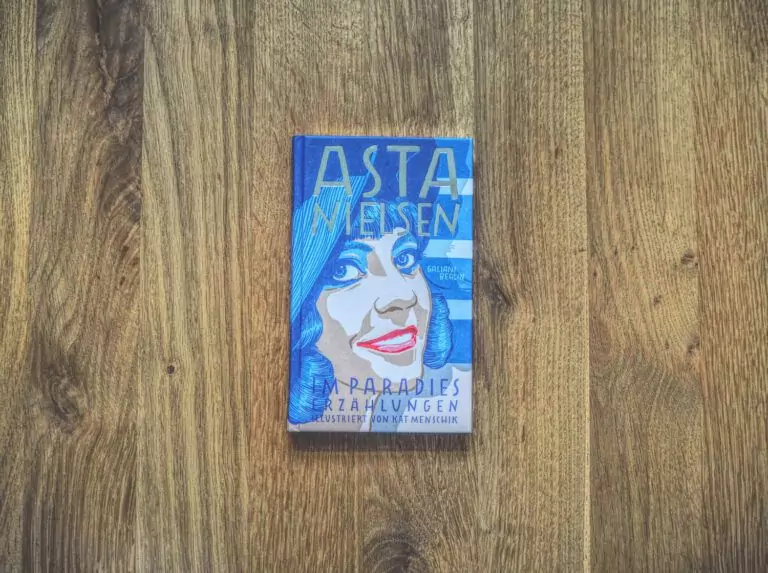 Ein Buch mit dem Bild einer Frau mit blauen Haaren, das auf einem Holztisch liegt.