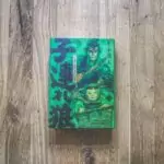 Ein Buch mit grünem Einband auf einem Holzboden.
