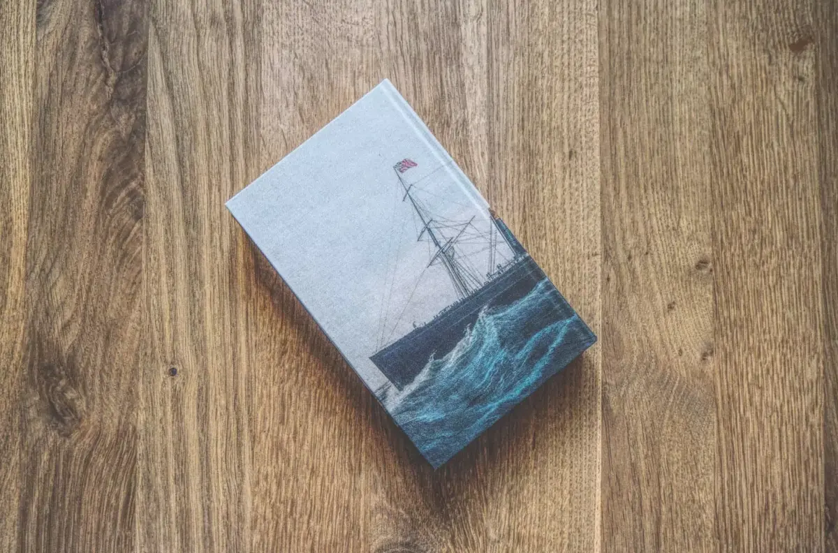 Ein Buch mit einem Gemälde eines Schiffes auf einem Holztisch.