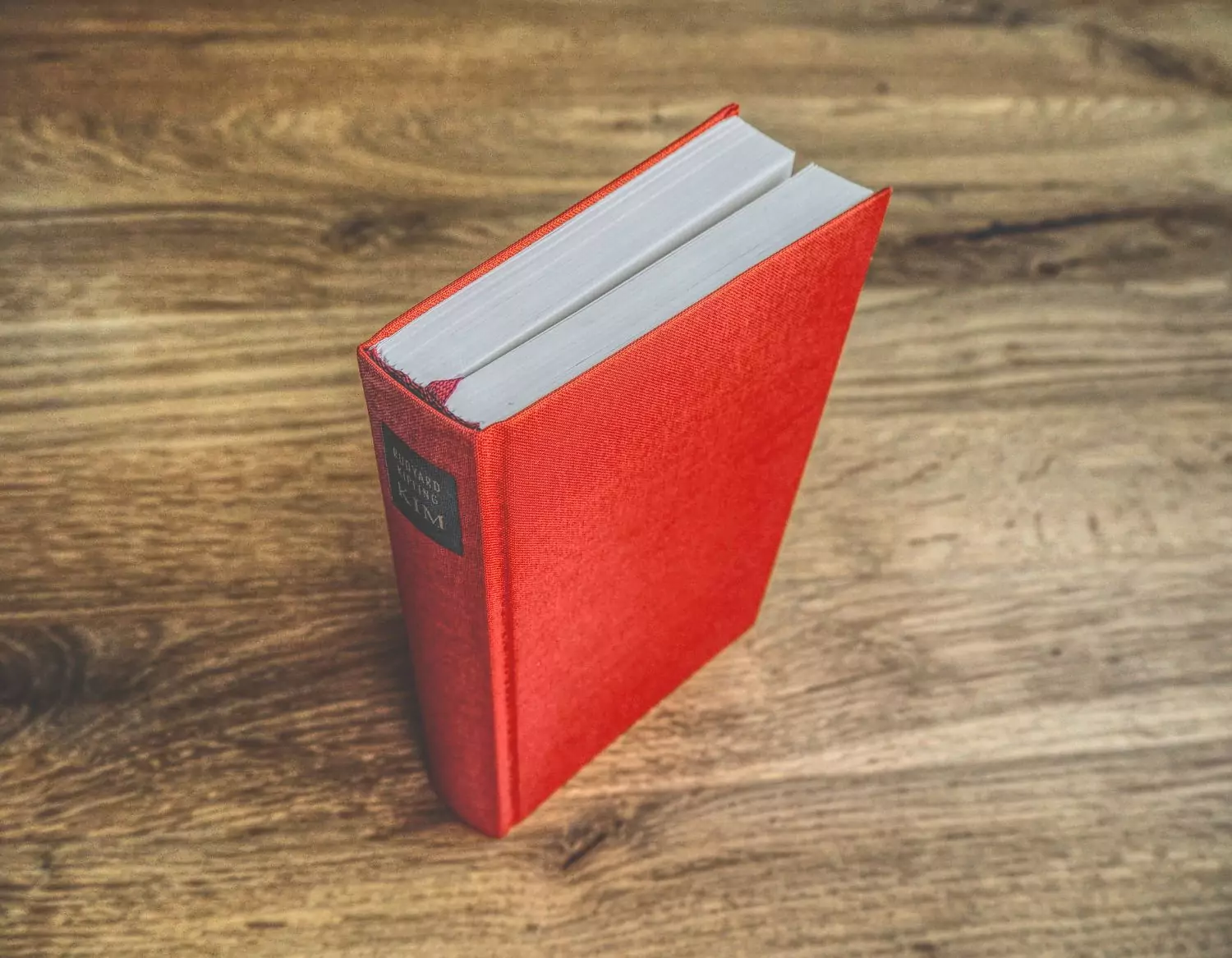 Ein rotes Buch auf einem Holztisch.