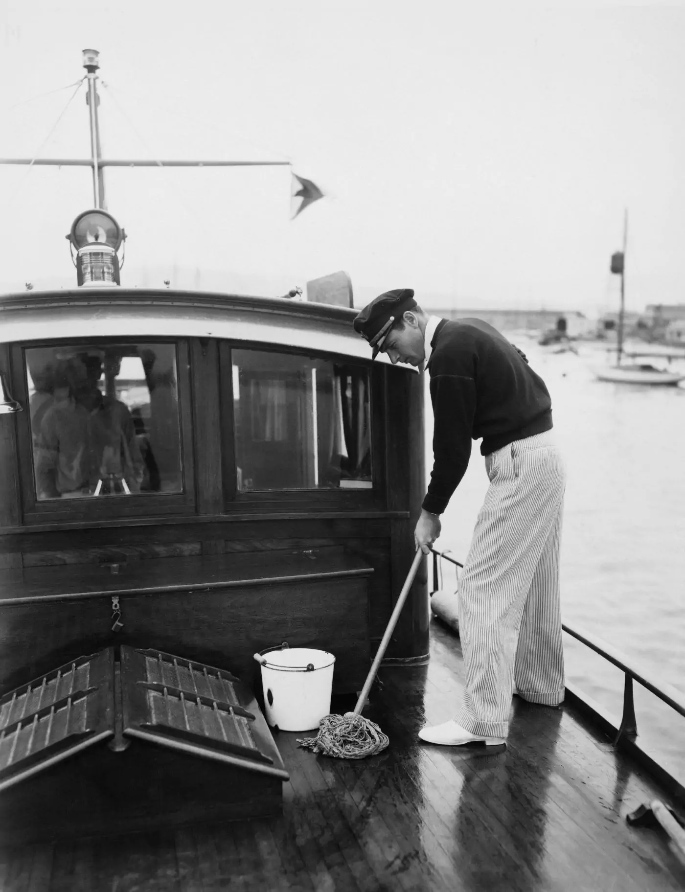 Ein Mann reinigt ein Boot mit einem Eimer.