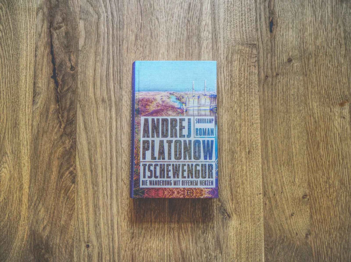 Eine deutsche Ausgabe des Buches "Tschewengur" von Andrei Platonow liegt auf einer Holzfläche.