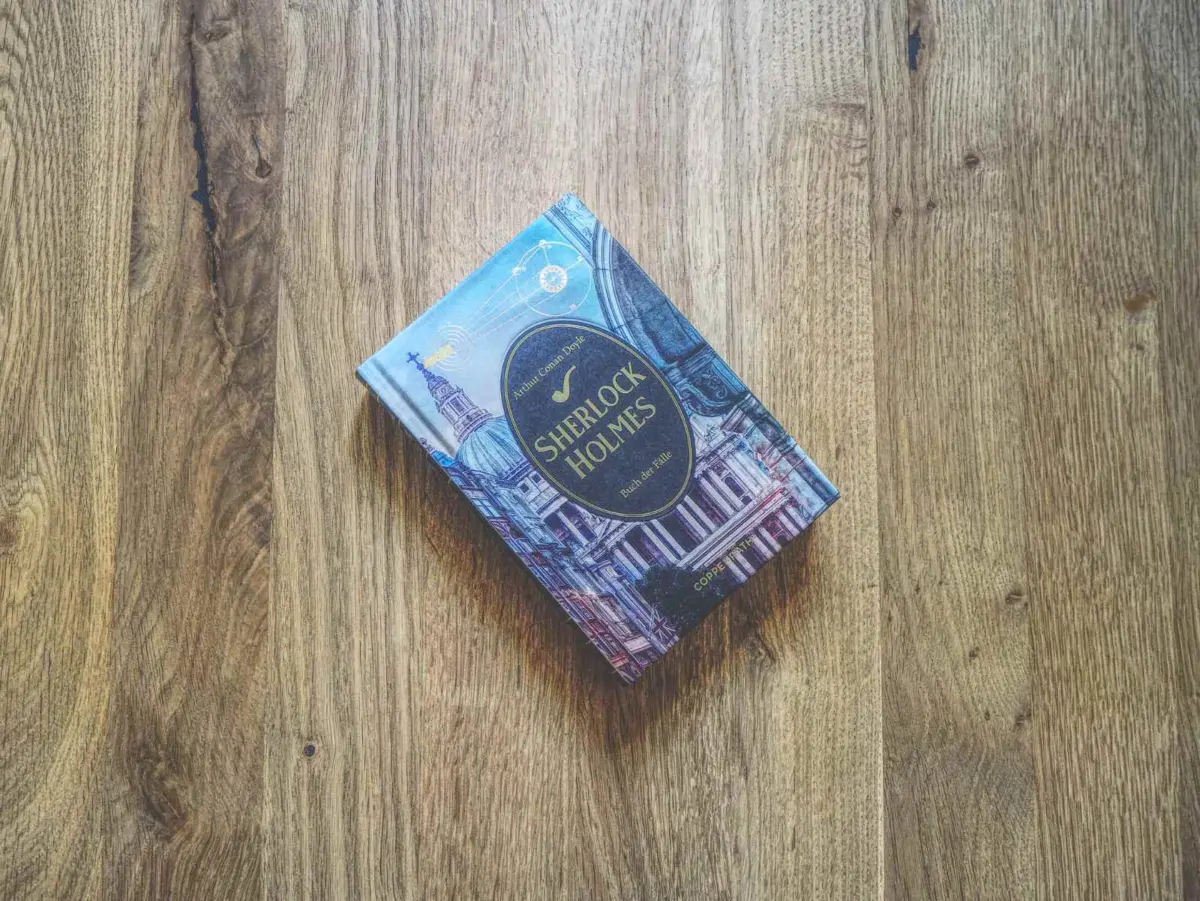 Eine gebundene Ausgabe von Sherlock Holmes liegt auf einem Holztisch.