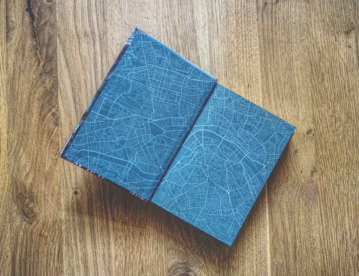 Auf einer hölzernen Unterlage liegt ein aufgeschlagenes Buch mit blauem Vorsatzpapier und weißem Straßenkartenmuster.
