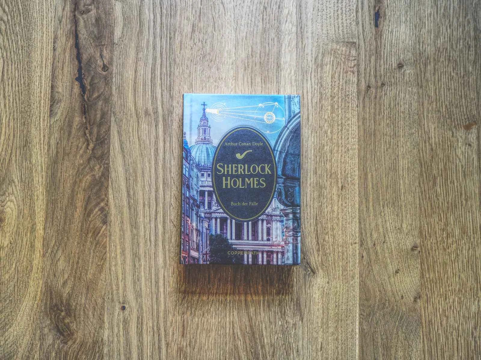 Ein gebundenes Exemplar von "Sherlock Holmes" von Arthur Conan Doyle wird auf eine hölzerne Unterlage gelegt.