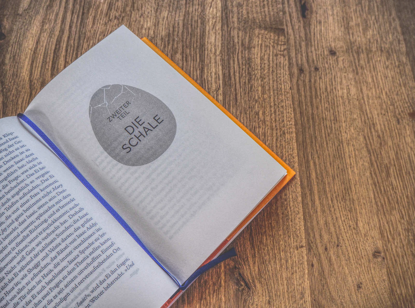 Aufgeschlagenes Buch auf einem Holztisch mit sichtbarer Titelseite mit der Aufschrift „Zweiter Teil Die Schale“ in deutscher Sprache.