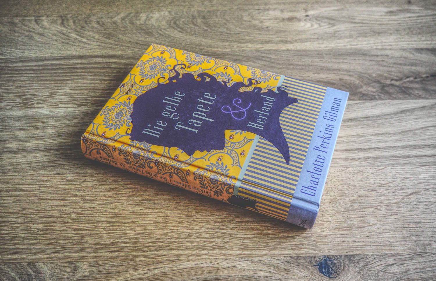 Ein gelb-violettes Buch auf einem Holztisch.
