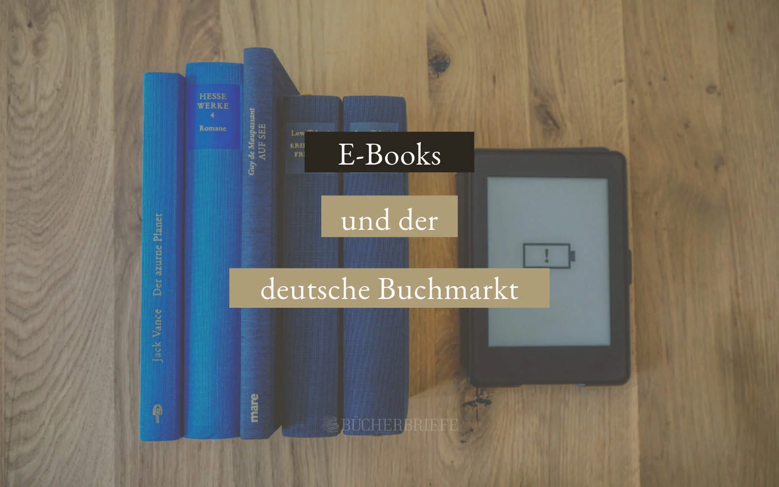 Stapel blauer Bücher neben einem E-Reader mit Ladesymbol auf einer Holzoberfläche. Textüberlagerung: „E-Books und der deutsche Buchmarkt.