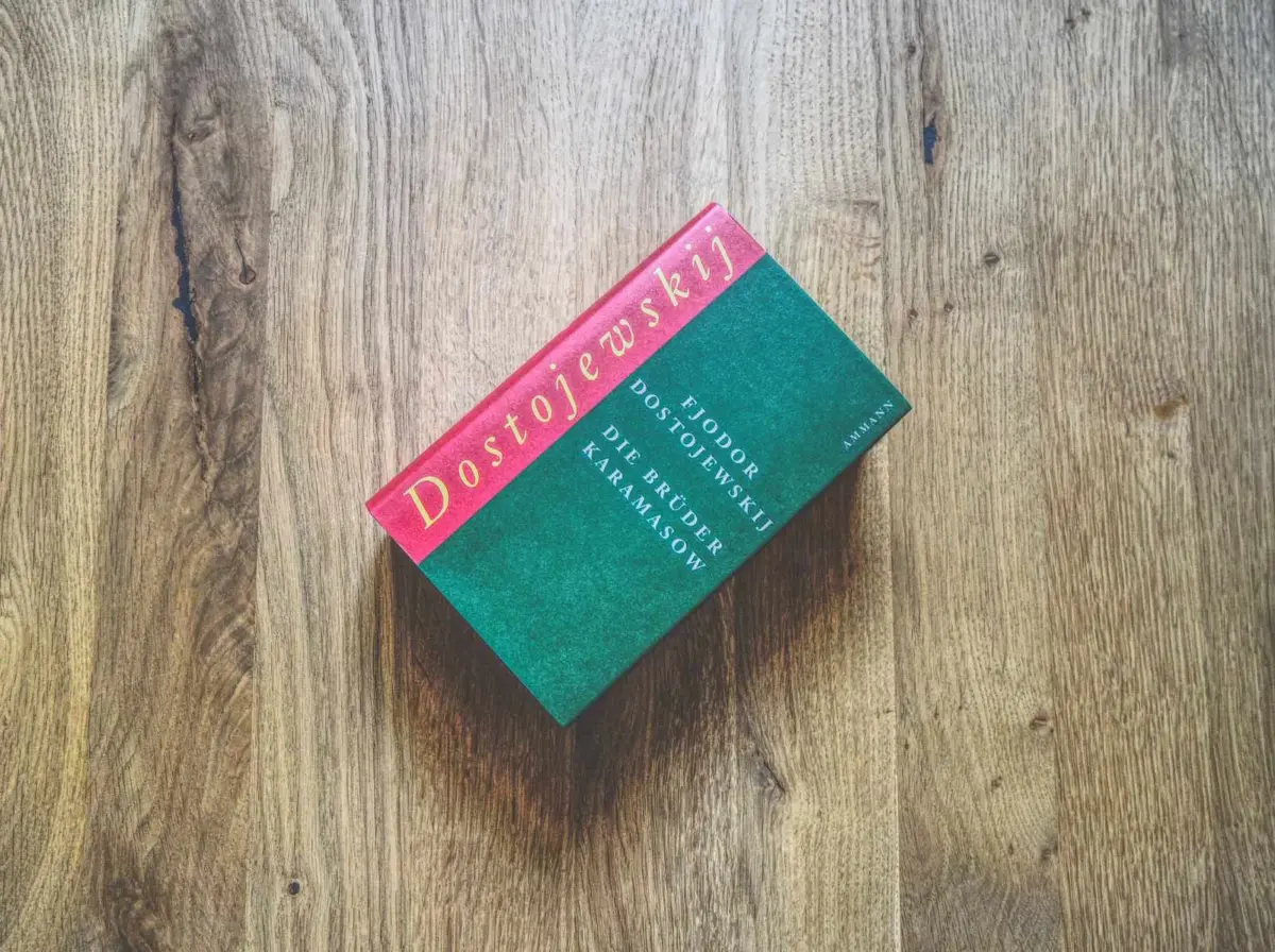 Ein gebundenes Exemplar von Dostojewskis "Die Brüder Karamasow" liegt auf einer Holzfläche.