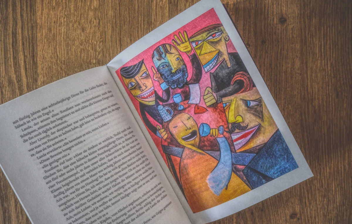 Offenes Buch auf einem Holztisch mit einer abstrakten Kunstillustration mit lebendigen Farben auf einer Seite und Text auf der gegenüberliegenden Seite.