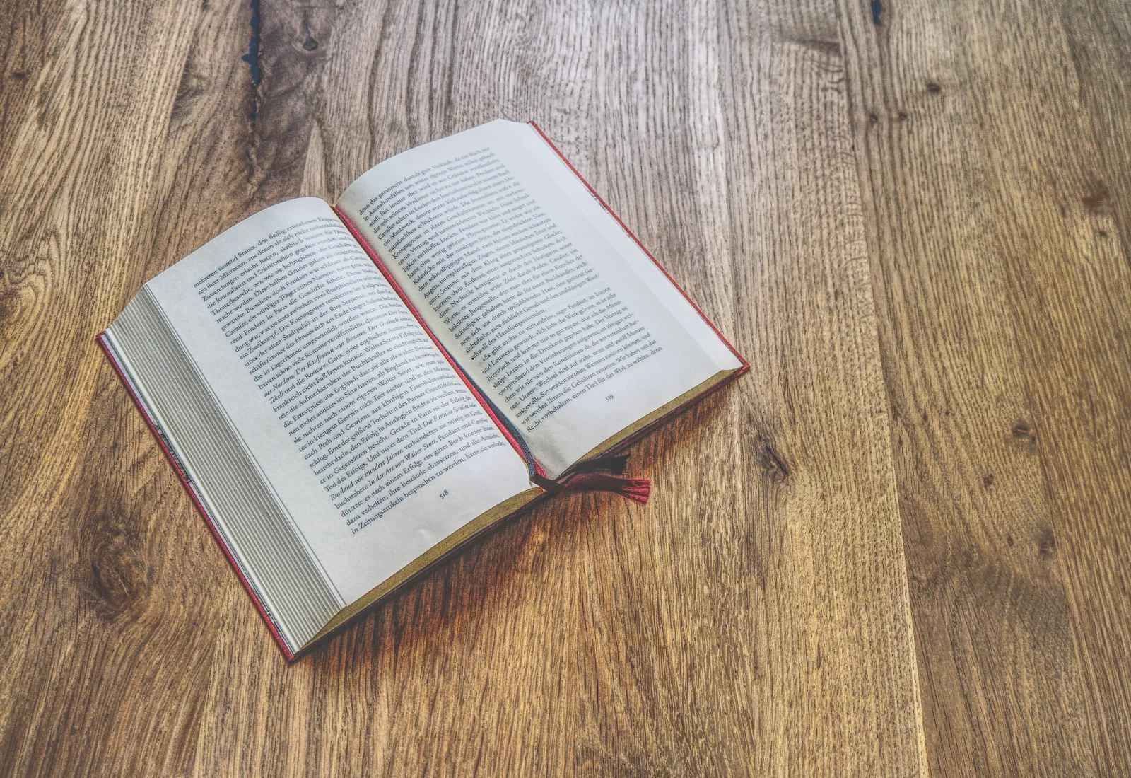 Ein aufgeschlagenes Buch mit Text liegt auf einer Holzfläche.