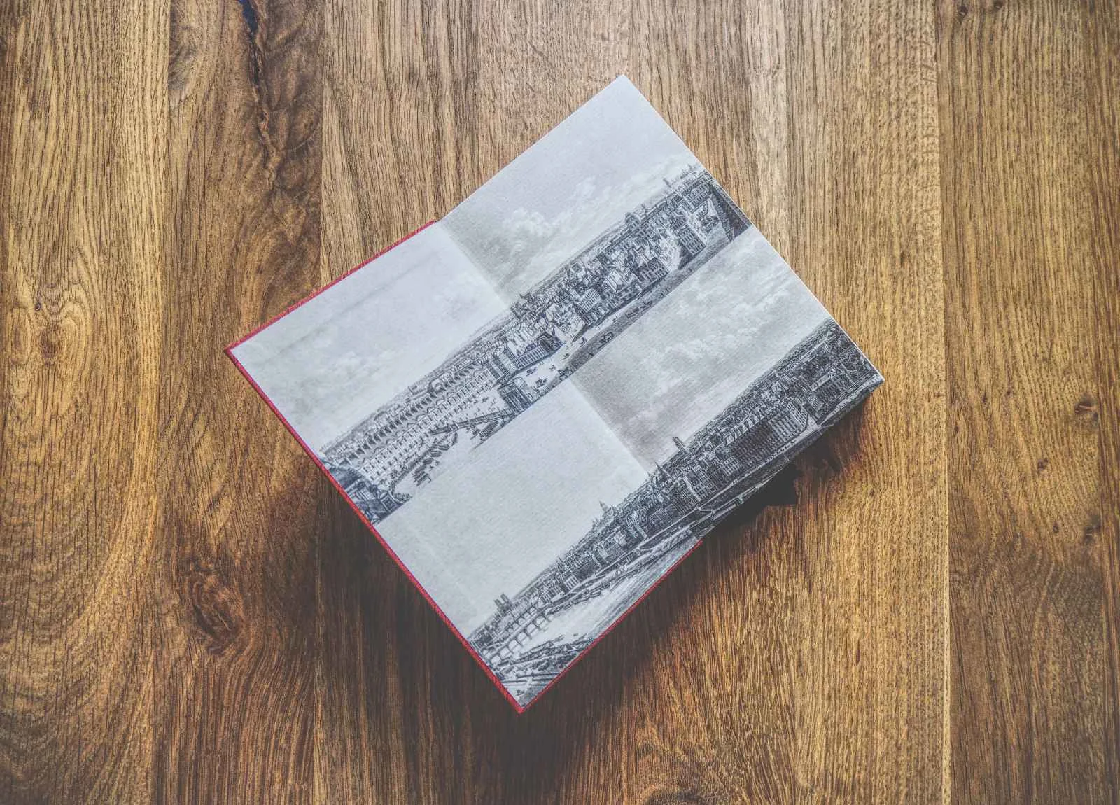 Ein aufgeschlagenes Buch mit schwarz-weißen Architekturillustrationen auf einer Holzoberfläche.