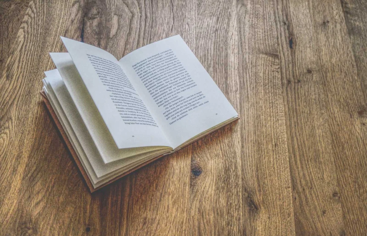 Ein offenes Buch mit gedrucktem Text liegt auf einer Holzoberfläche.