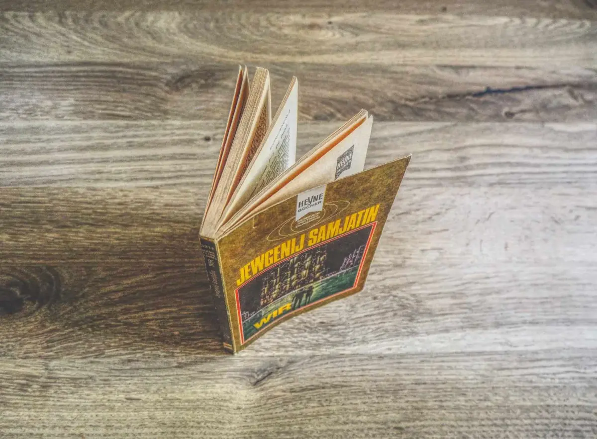 Ein Buch mit gelb-braunem Einband und dem Titel "Jewgenij Samjatin" steht aufgeschlagen auf einer Holzplatte.