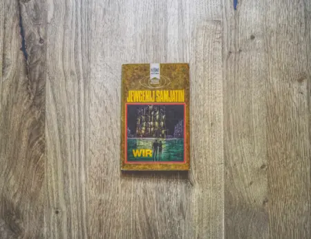 Ein Exemplar des Buches "Wir" von Jewgenij Samjatin liegt auf einer Holzfläche.