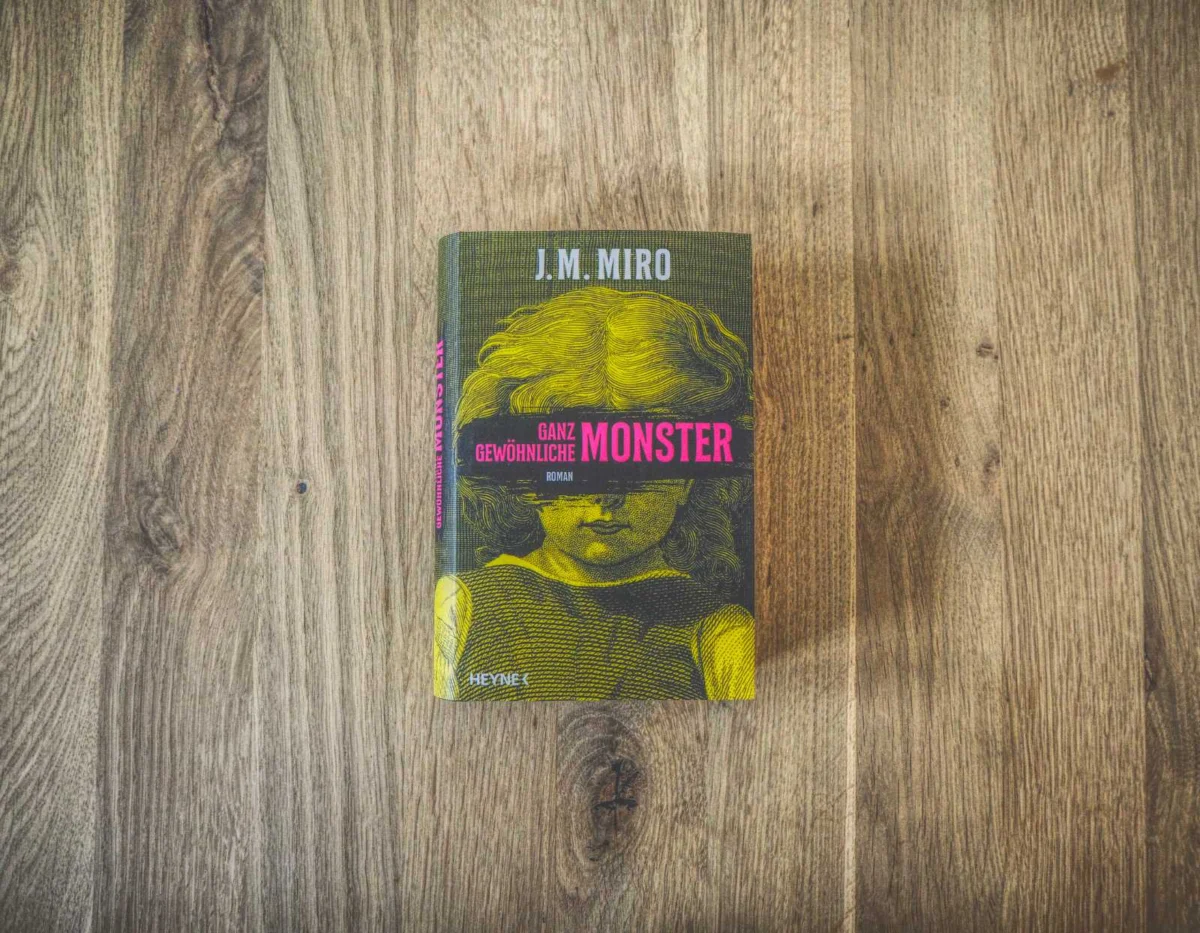 Auf einer Holzfläche liegt ein Buch mit dem Titel „Ganz Gewöhnliche Monster“ von J.M. Miro. Auf dem Buchdeckel ist ein Kind abgebildet.