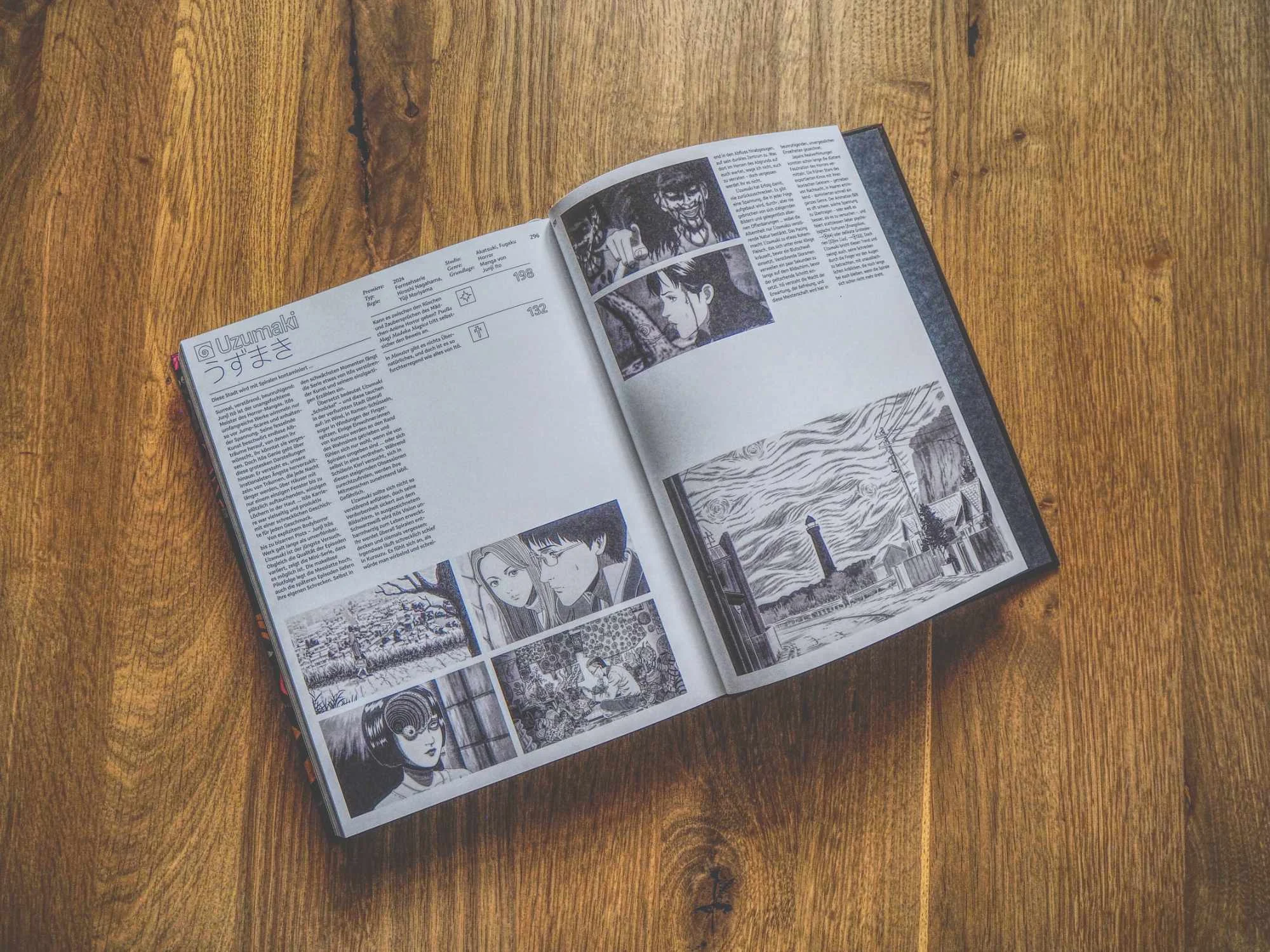 Ein aufgeschlagenes Buch mit Seiten mit japanischem Text und mehreren schwarz-weißen Manga-Illustrationen auf einer Holzoberfläche.