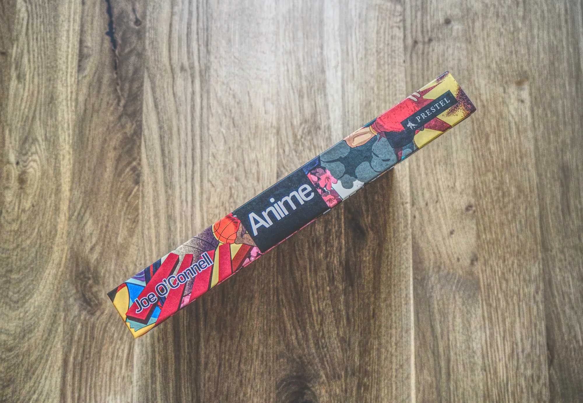 Der Buchrücken eines bunten Buches mit dem Titel "Anime" von Joe O'Connell, erschienen bei Prestel, auf einer hölzernen Oberfläche.