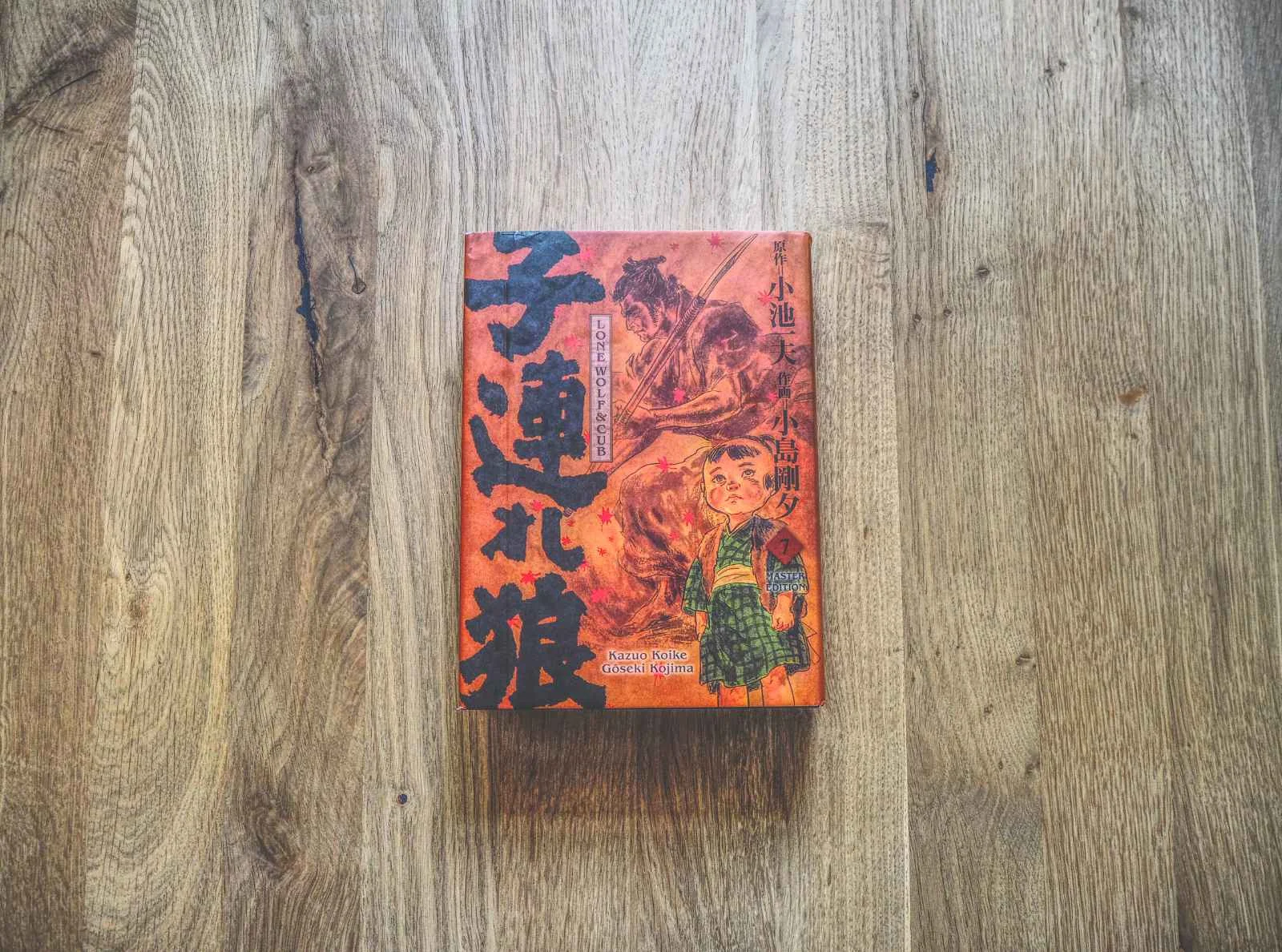 Ein japanisches Buch mit einem illustrierten Einband, auf dem ein Kind und ein Wolf abgebildet sind, liegt auf einer Holzfläche.