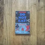 Ein Buch mit dem Titel „Don’t eat“ liegt auf einem Holzboden.