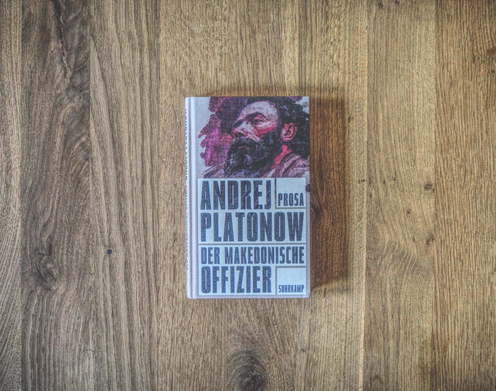 Auf einer Holzfläche liegt ein Buch mit dem Titel „Andrej Platonow: Der Makedonische Offizier“. Auf dem Cover ist das Porträt eines Mannes mit Bart zu sehen.