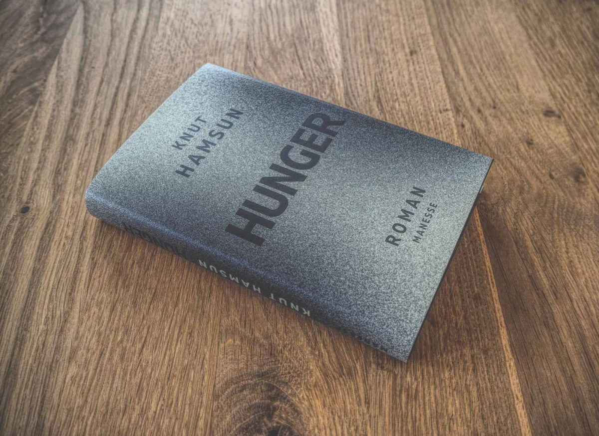 Ein gebundenes Buch mit dem Titel „Hunger“ von Knut Hamsun auf einer Holzoberfläche.