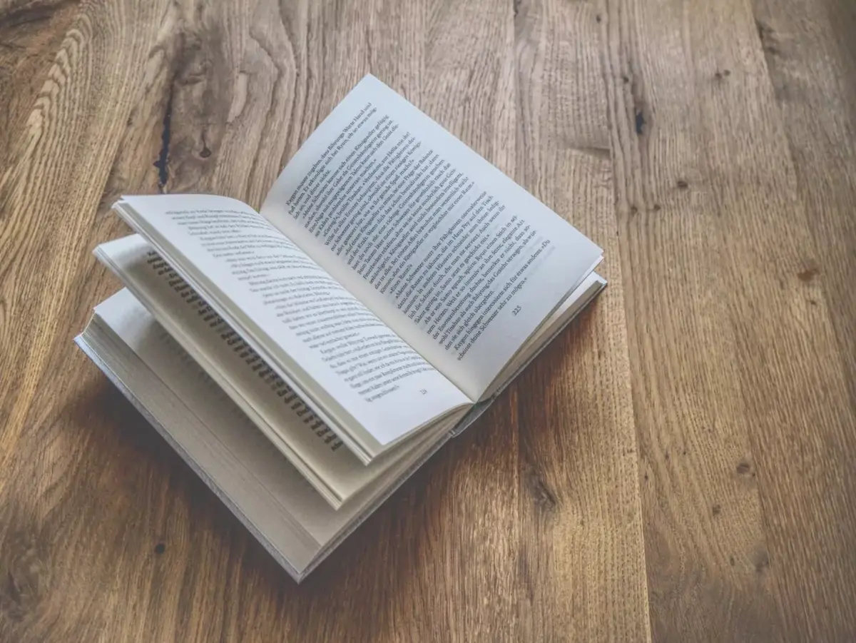 Ein offenes Buch mit umgeblätterten Seiten auf einem Holztisch.