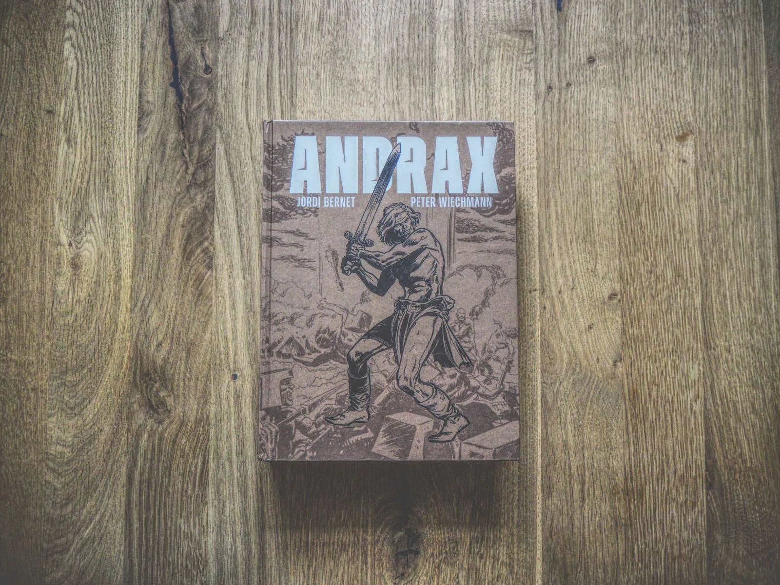 Auf einer Holzfläche liegt ein Buch mit dem Titel „ANDRAX“ von Jordi Bernet und Peter Wiechmann, auf dessen Cover eine kriegerische Figur abgebildet ist.