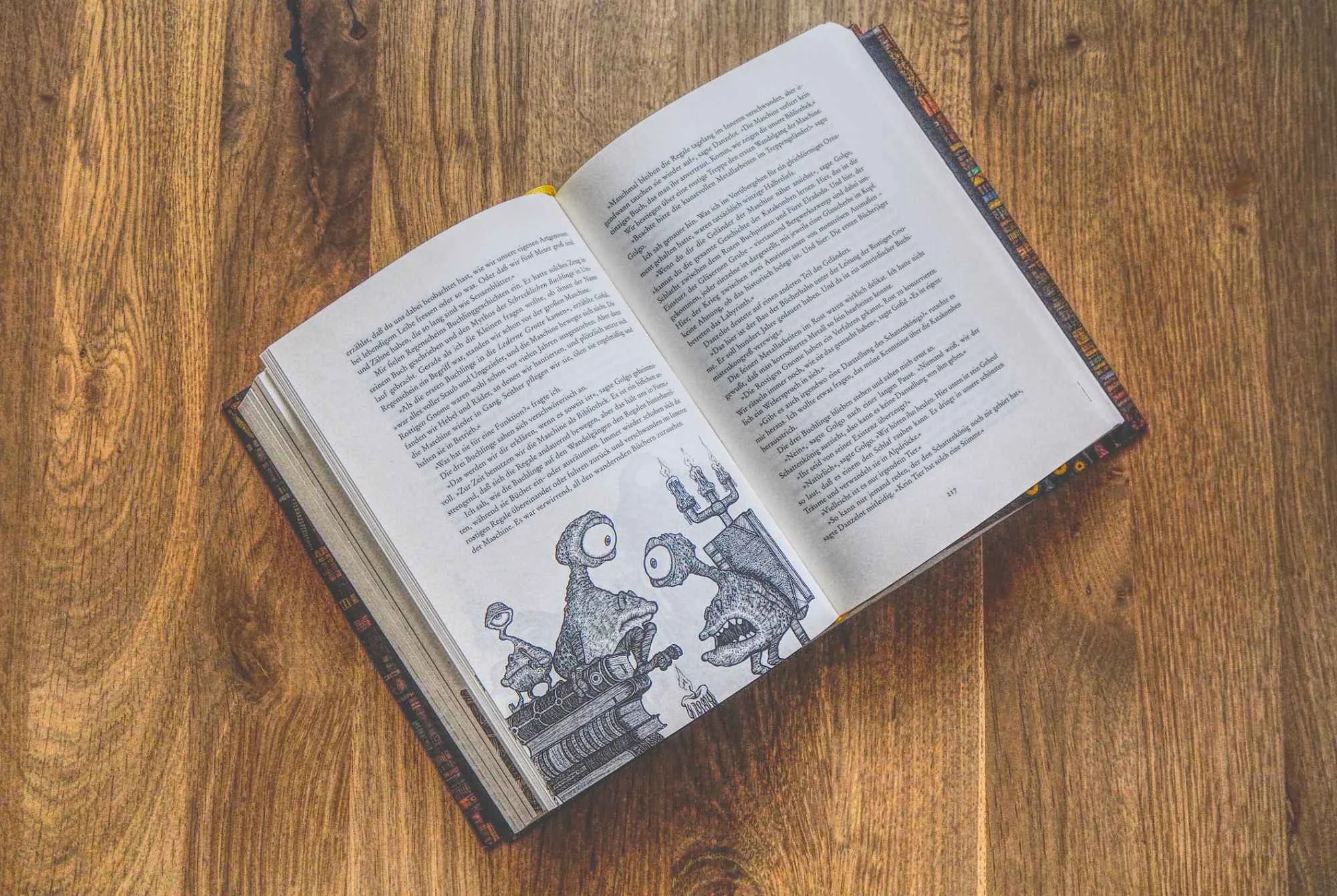 Auf einer hölzernen Unterlage liegt ein aufgeschlagenes Buch, das auf beiden Seiten Text und auf der linken Seite eine schwarz-weiße Illustration von Robotern zeigt.